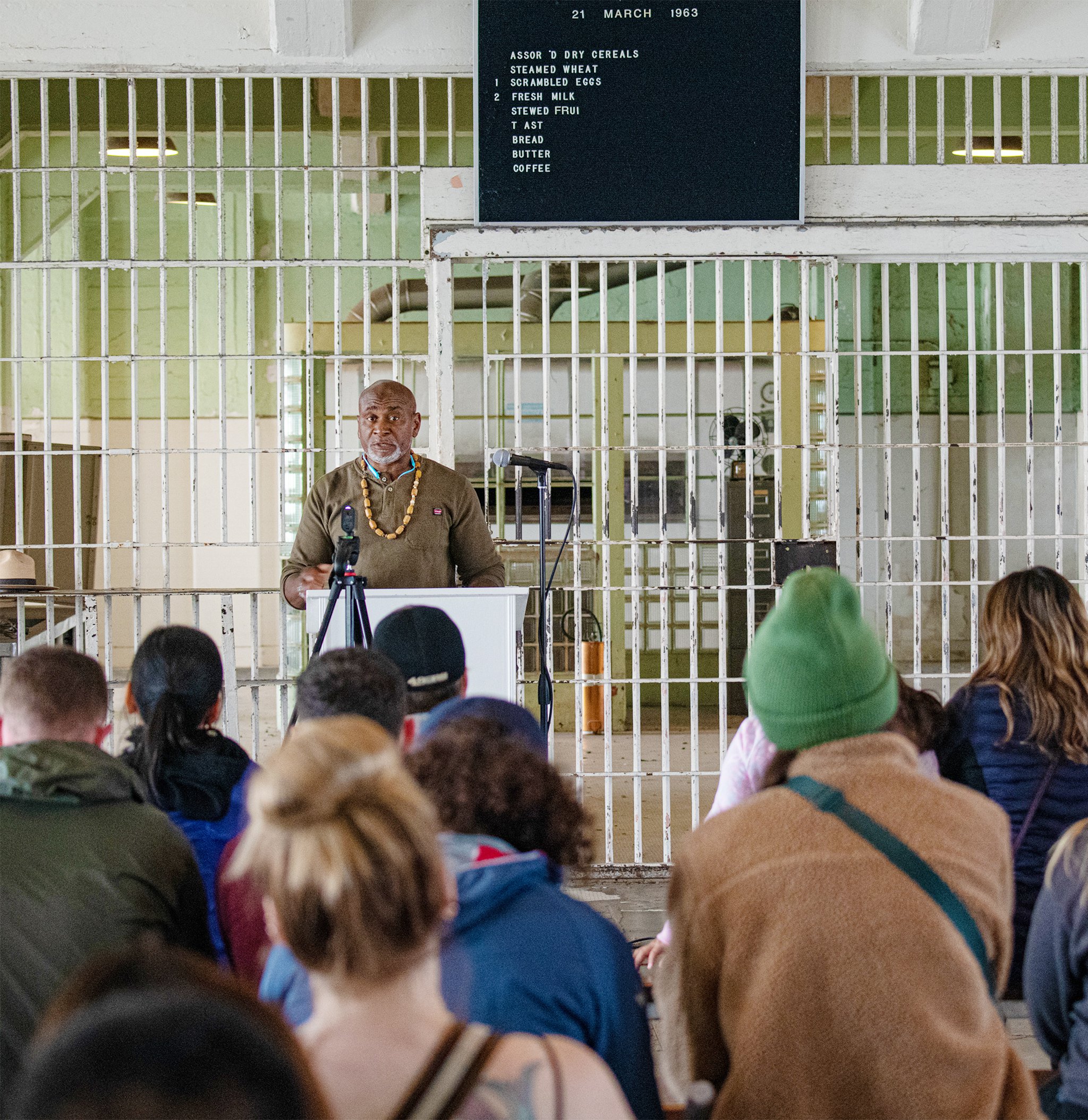 Troy Williams, formerly incarcerated speaker and founder of Restorative Media Inc., gives a talk before an audience in the dining hall at Alcatraz. Photo by Dave Rauenbuehler.